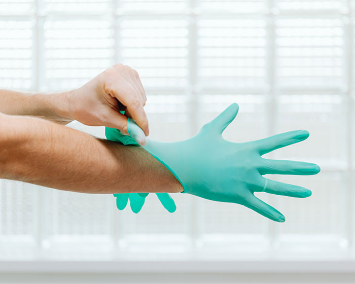 Person putting on plastic gloves preparing for epoxy countertops application or renovation work indoors.