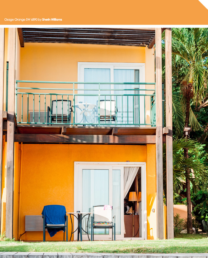 Orange painted house exterior with balcony and patio furniture, showcasing vibrant exterior house colors to turn heads in the neighborhood.