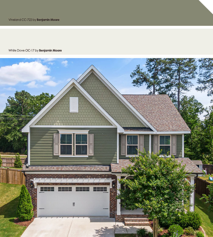 Light green exterior house colors with brick accents on a two-story suburban home surrounded by greenery.