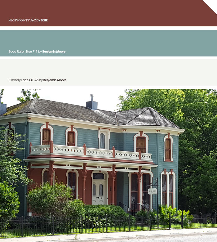 Dark red and light blue exterior house colors on a classic two-story home surrounded by greenery in the neighborhood.
