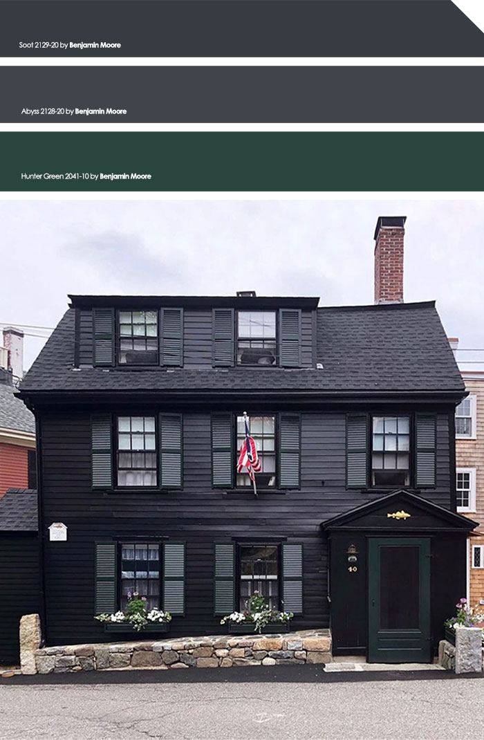 Black painted exterior house with dark shutters and stone foundation, showcasing one of the top exterior house colors.