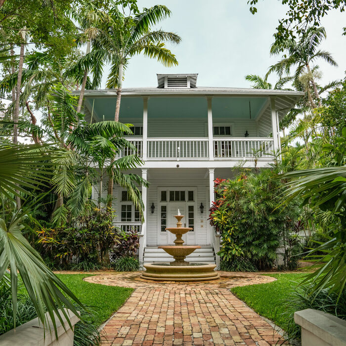 White house with outdoor fountain and trees