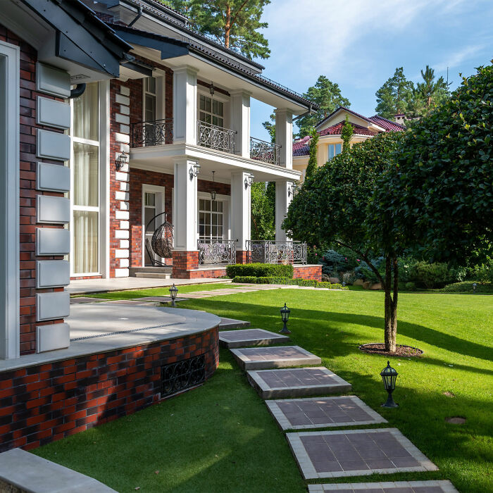 Cottage exterior near plants with trees and pathway in yard