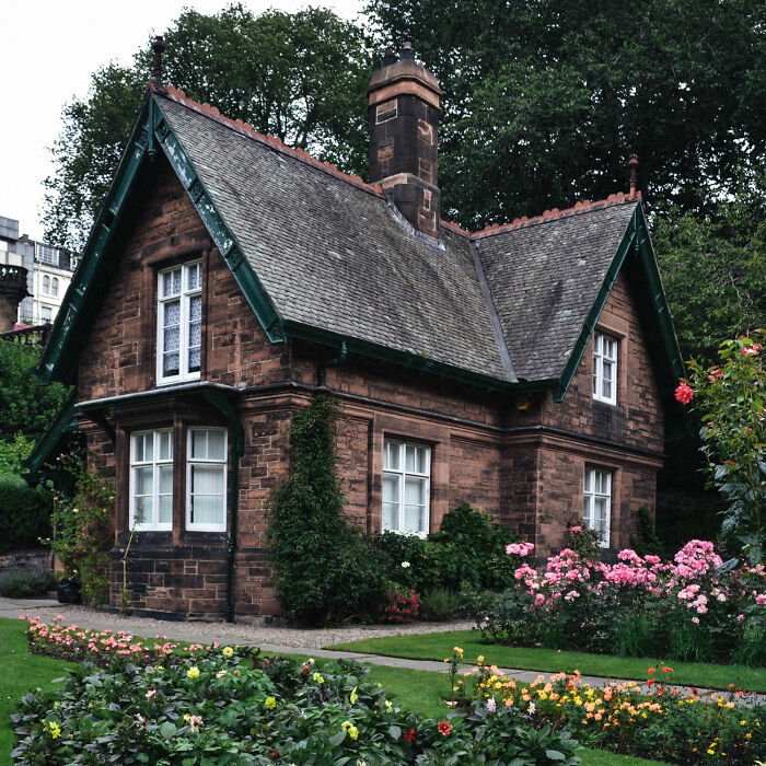 Brown and white concrete house with front yard with flowers
