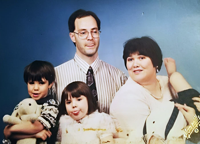 Family photo with parents and two children making funny faces, capturing a hilarious family moment.