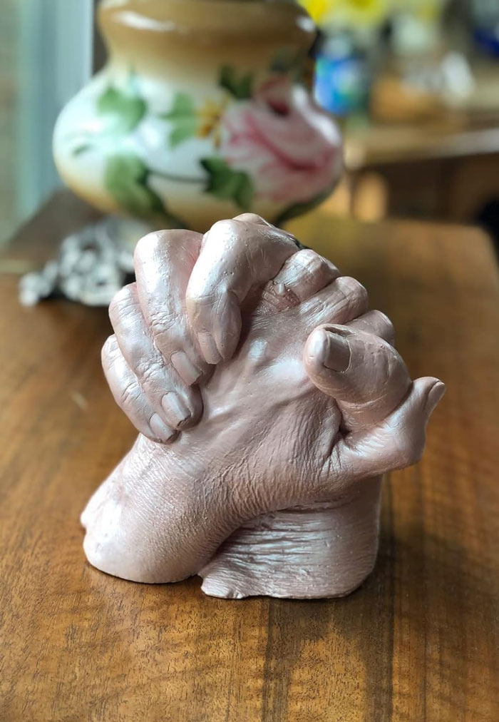 Sculpted hands intertwined as a unique gift idea for the partner who’s seen it all on a wooden table.