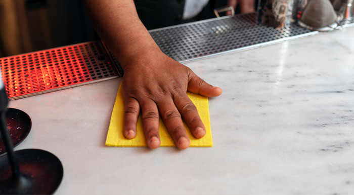 A person wearing gloves and cleaning a white granite countertop A person wearing gloves and cleaning a white granite countertop