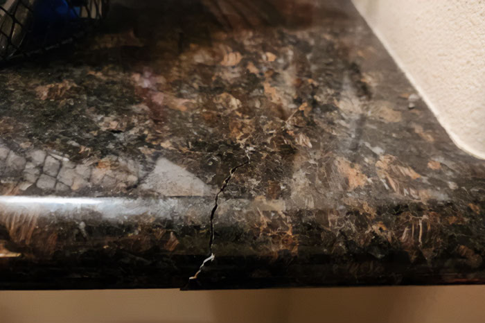 Close-up of a brown granite countertop that is cracked. Close-up of a brown granite countertop that is cracked.
