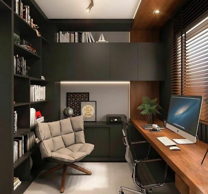 Cozy home office design with built-in shelves, comfortable chair, wooden desk, and natural light through blinds.