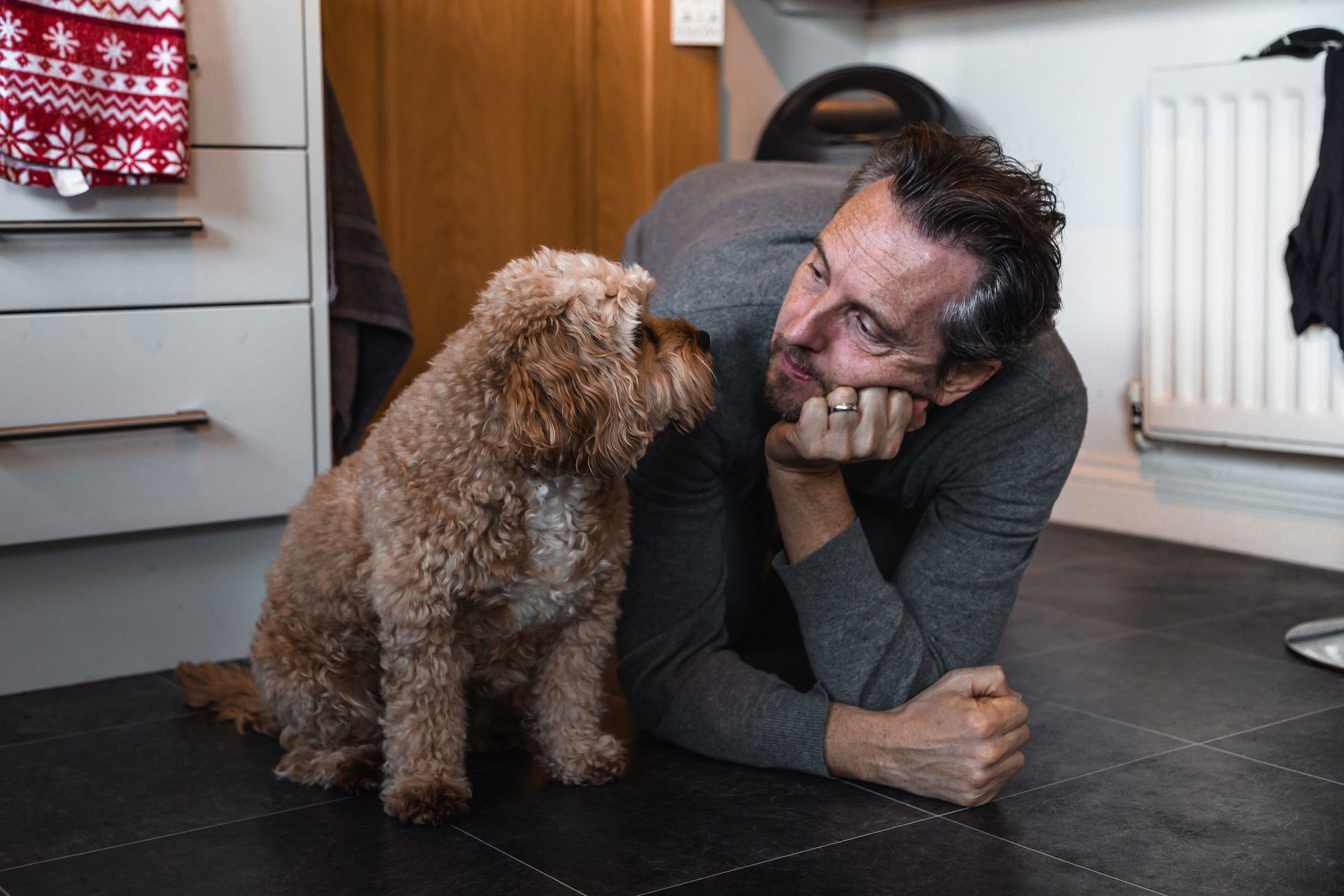 Man showing love to his dog by lying on the floor and making eye contact.