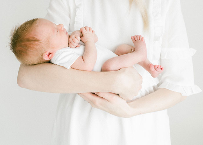 Newborn baby with unique hair color held by mother, highlighting surprise and paternity test themes in family setting.