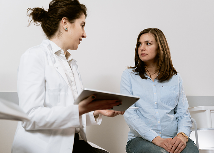 Woman anxiously listens to doctor holding tablet during paternity test discussion about baby&rsquo;s hair color and results.
