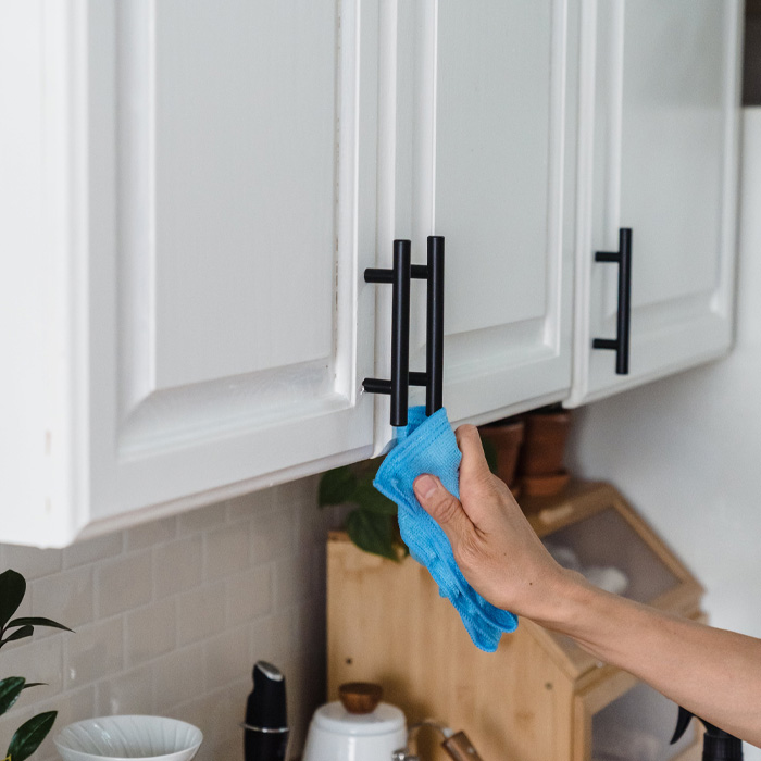 Person cleaning kitchen cabinets