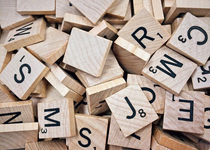 Wooden Scrabble tiles scattered in a pile, illustrating weird surprises people found after moving into a new home.