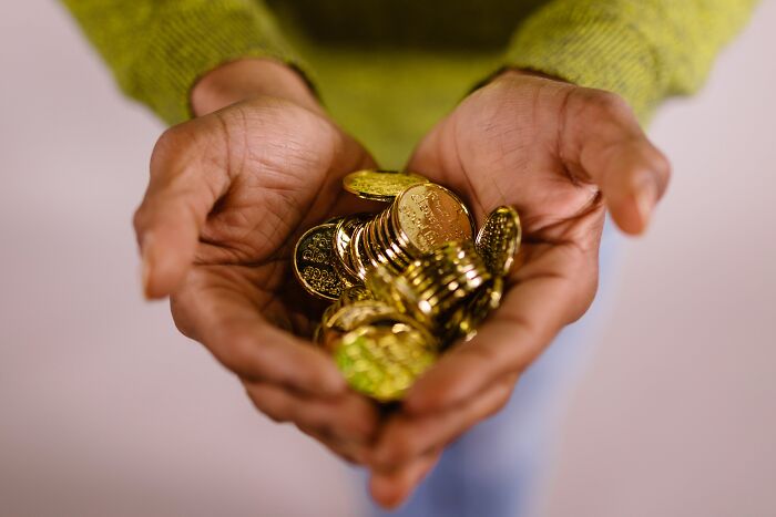 Hands holding a handful of shiny gold coins, symbolizing weird surprises people found after moving into a new home.