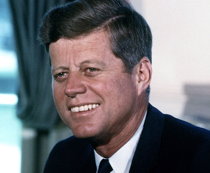 A smiling man in formal attire, associated with interesting facts not commonly taught in school.