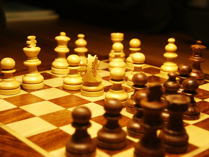 Chessboard with wooden pieces set up for an intriguing game, captured in warm lighting.