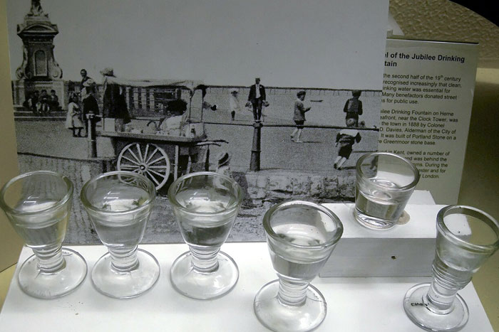 Glasses of water displayed in front of a historical street scene, representing intriguing facts not learned in school.