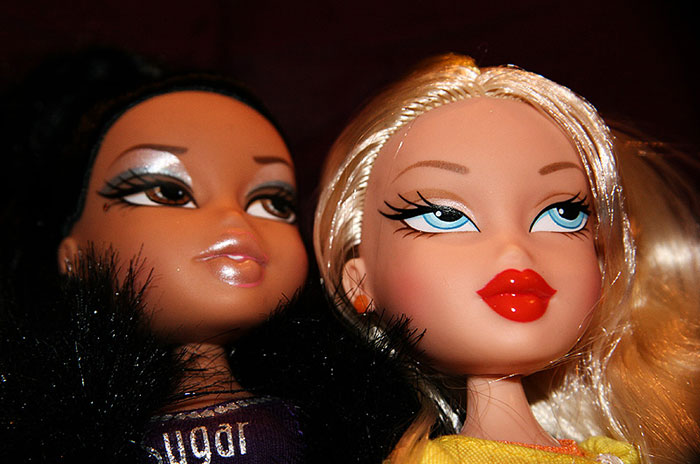 Two fashion dolls with bold makeup and stylish outfits, illustrating intriguing facts often missed in school.