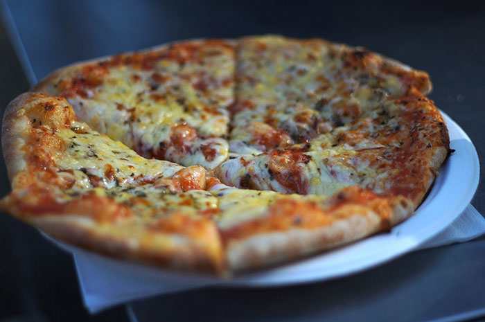 A freshly baked cheese pizza on a white plate, showcasing its delicious crust and toppings.