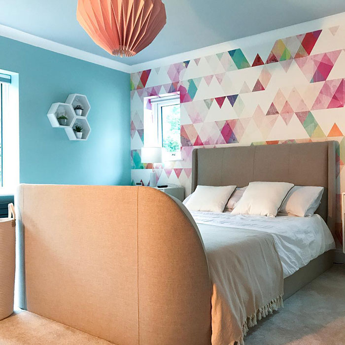 Bedroom wall painting design with colorful triangle patterns, modern decor, and a cozy beige upholstered bed.