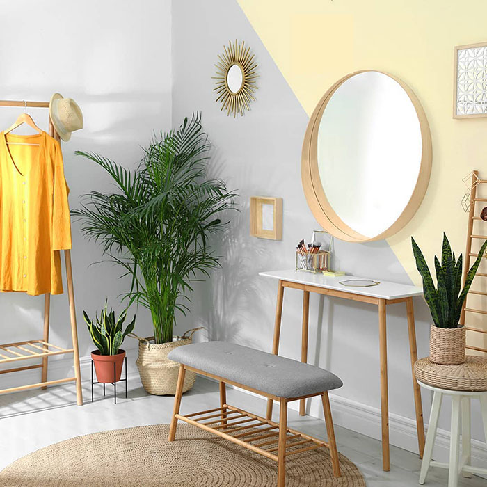 Boho style room with natural wood furniture and wall painting design featuring geometric color blocks and decorative plants.