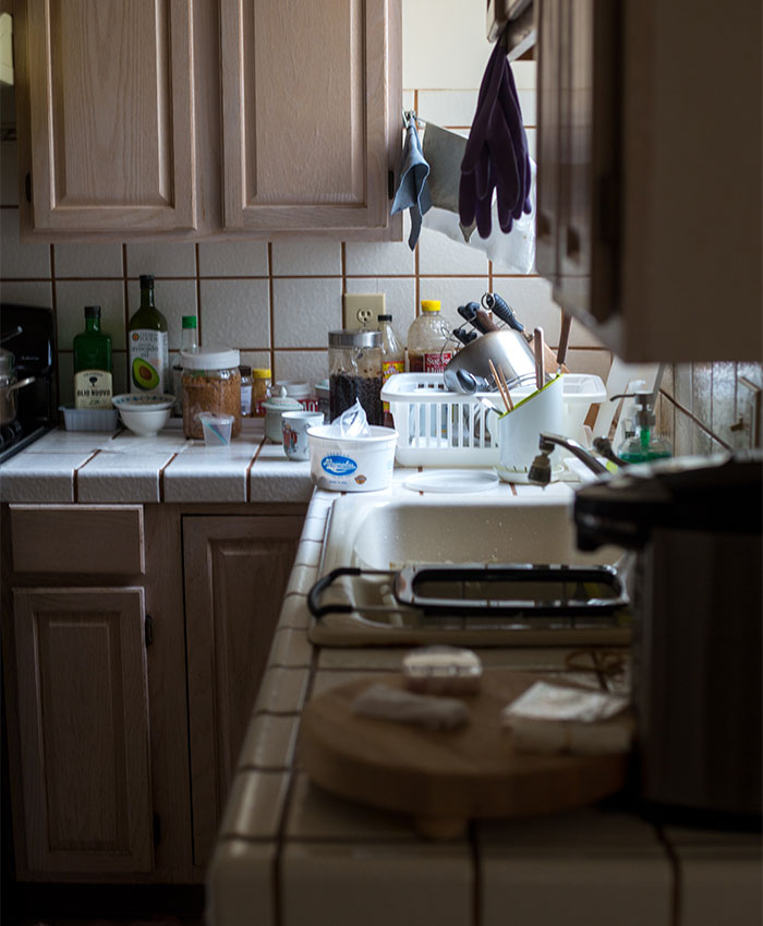 Cluttered kitchen countertop and sink symbolizing family tension around mom kicking out husband and son before Christmas.