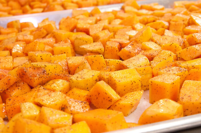 Cubed butternut squash, seasoned and arranged on a baking tray, a grocery store item.