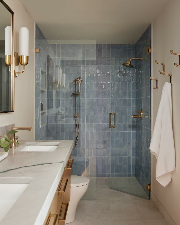 Pale blue colored walk-in shower with brass fixtures 