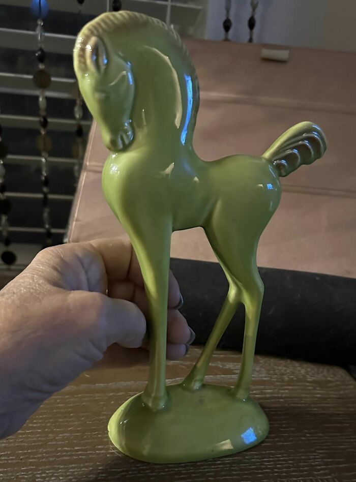 Glossy green ceramic horse figurine held by hand, found luck at thrift stores and flea markets.