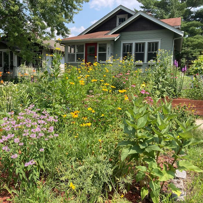 Green house with flowers in front yard