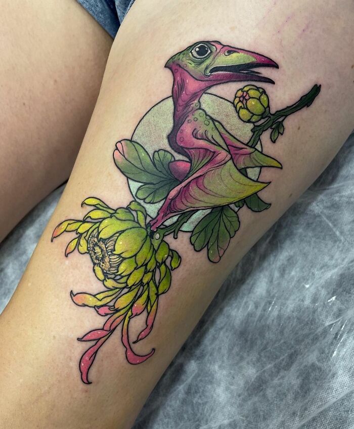 Colorful dinosaur tattoo with floral elements perfectly executed on skin.