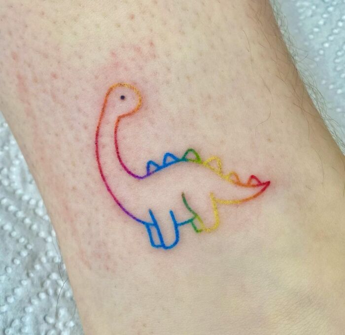 Colorful dinosaur tattoo with rainbow outlines perfectly executed on skin.