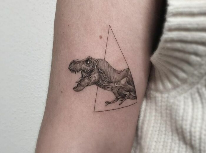 Triangular T-Rex dinosaur tattoo on arm, showcasing cool ink artistry and perfect e*******n.