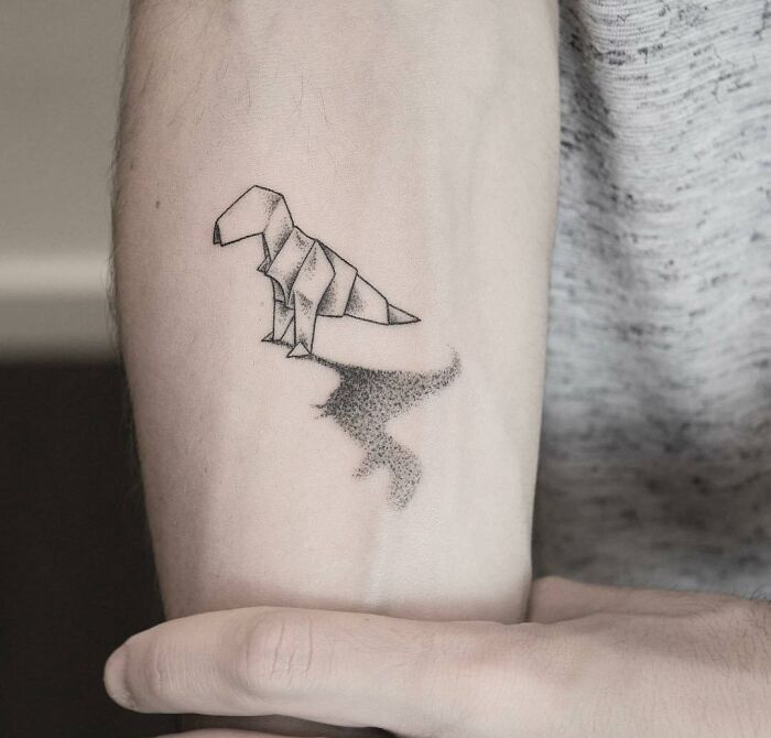 Origami dinosaur tattoo on an arm with a shadow design.
