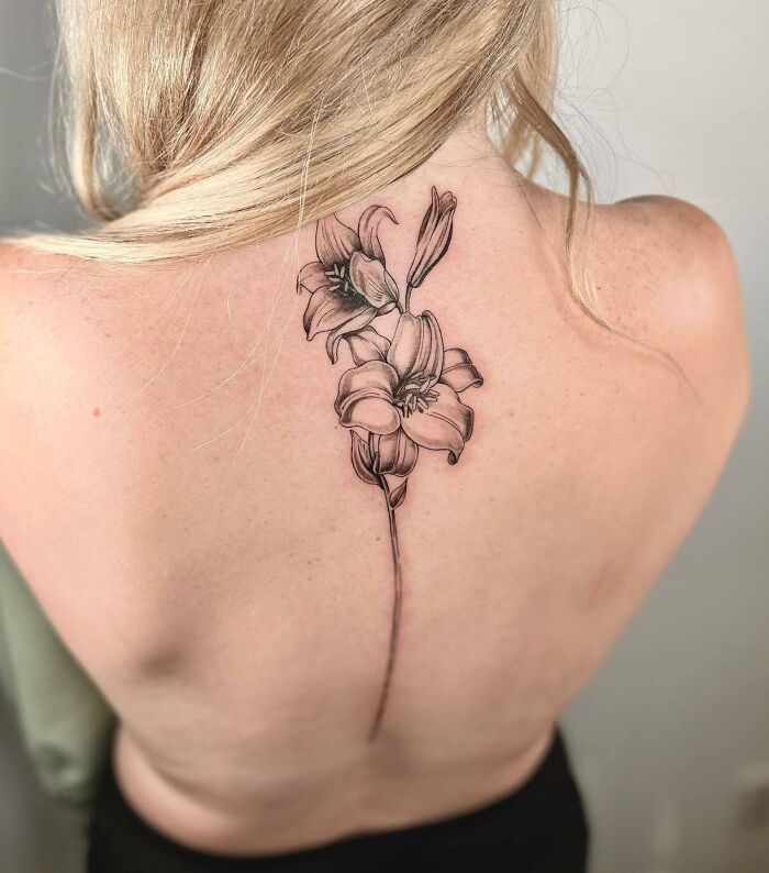 Floral spine tattoo on a woman's back featuring detailed flowers.