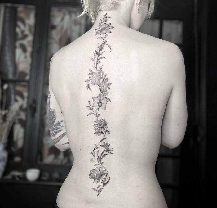 Elegant floral spine tattoo on a woman's back, showcasing intricate design and beauty.
