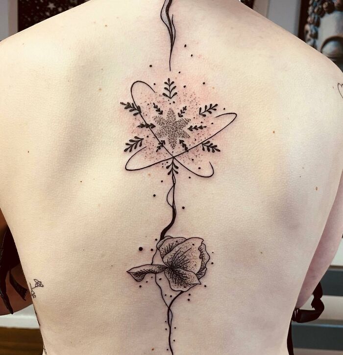 Beautiful spine tattoo with floral and geometric design in black ink.