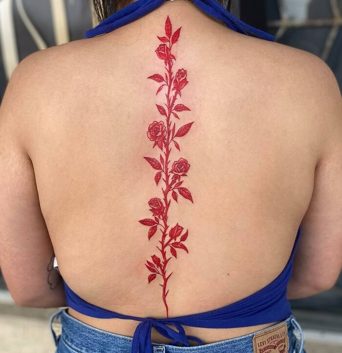Red rose spine tattoo on a woman's back, showcasing beautiful spine tattoos in intricate detail.