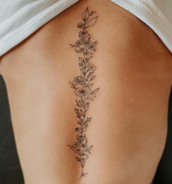 Floral spine tattoo design on a person's back showcasing intricate details and symmetry.
