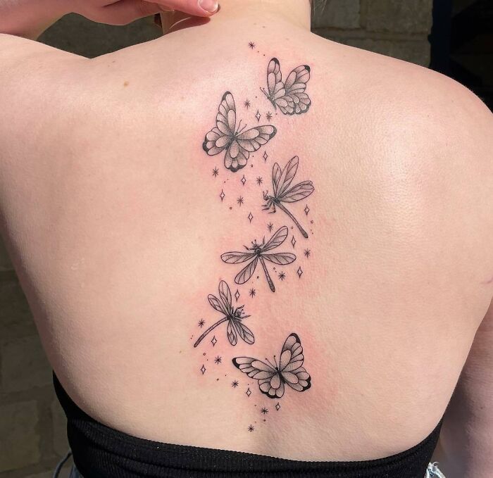 Intricate spine tattoo with butterflies and dragonflies on a woman's back.