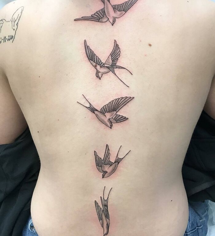 Beautiful spine tattoo with birds in flight along the back.