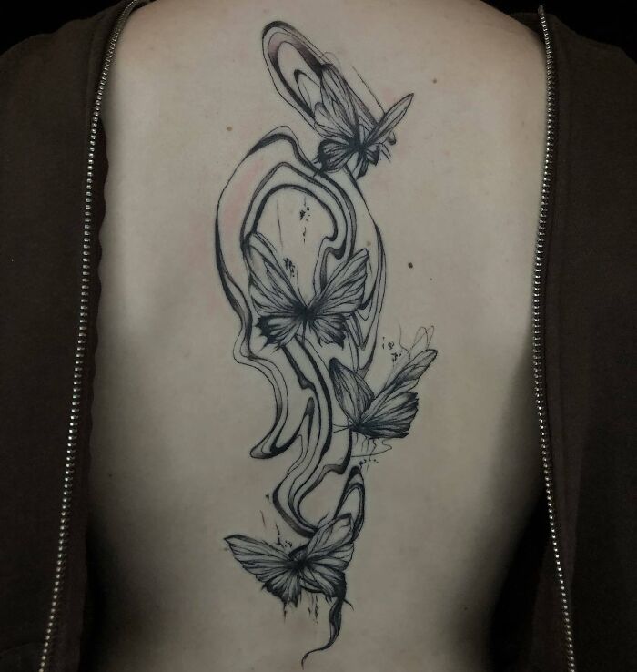 Butterfly spine tattoo with abstract design, showcasing beautiful black ink work along the back.