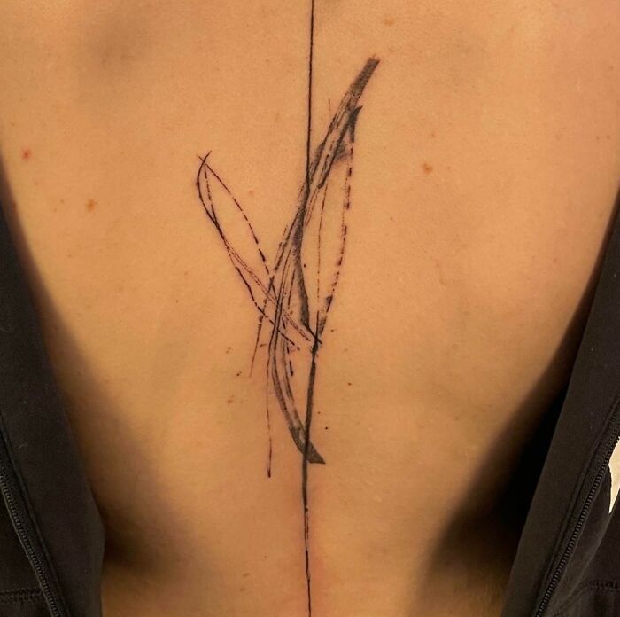 Abstract spine tattoo with minimalist lines on a person's back.