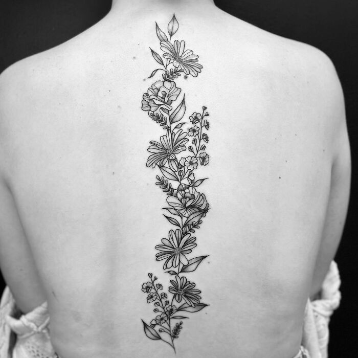Floral spine tattoo featuring delicate linework on a woman's back.