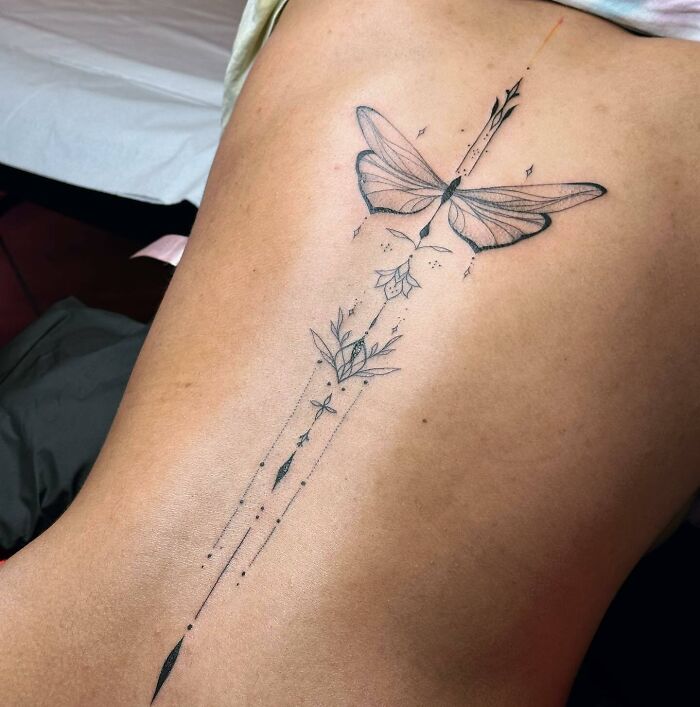 Elegant spine tattoo featuring a delicate moth and floral design, showcasing beauty on skin.