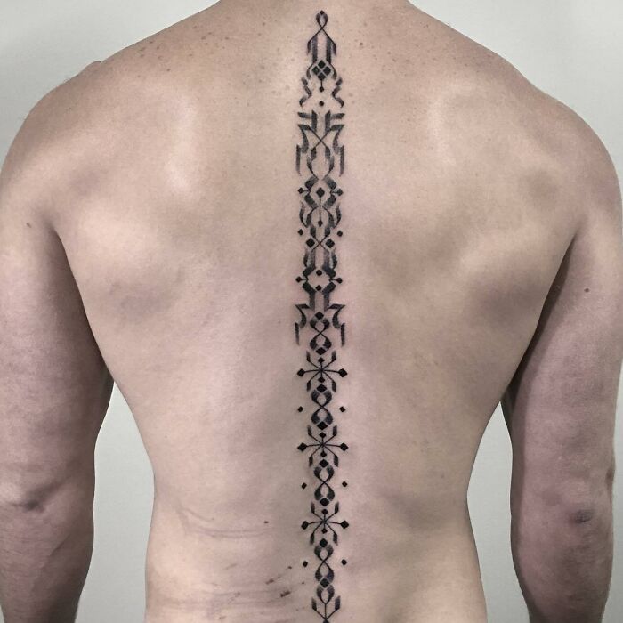 Intricate spine tattoo design on a person's back, showcasing beautiful and detailed artwork along the spine.