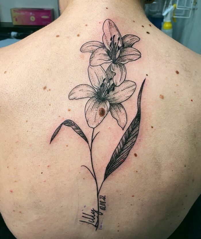 Floral spine tattoo featuring intricate lily design on a person's back.