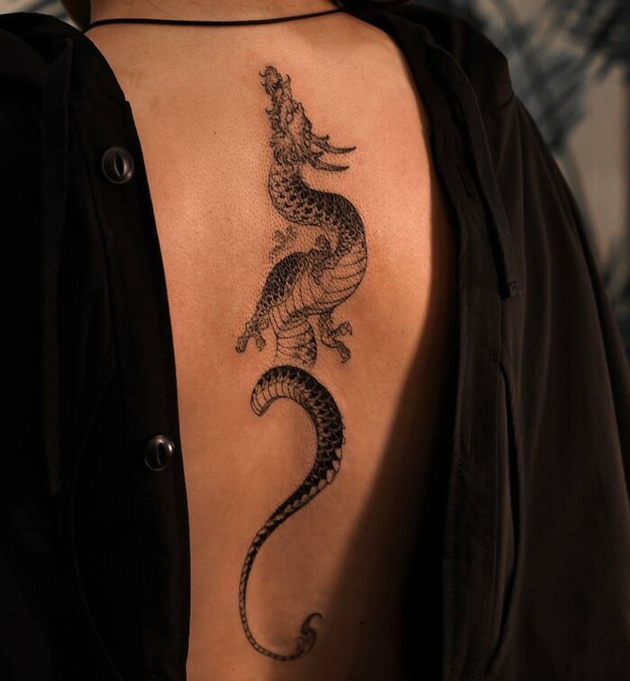 Dragon spine tattoo design on a person's back, showcasing intricate details and bold lines.