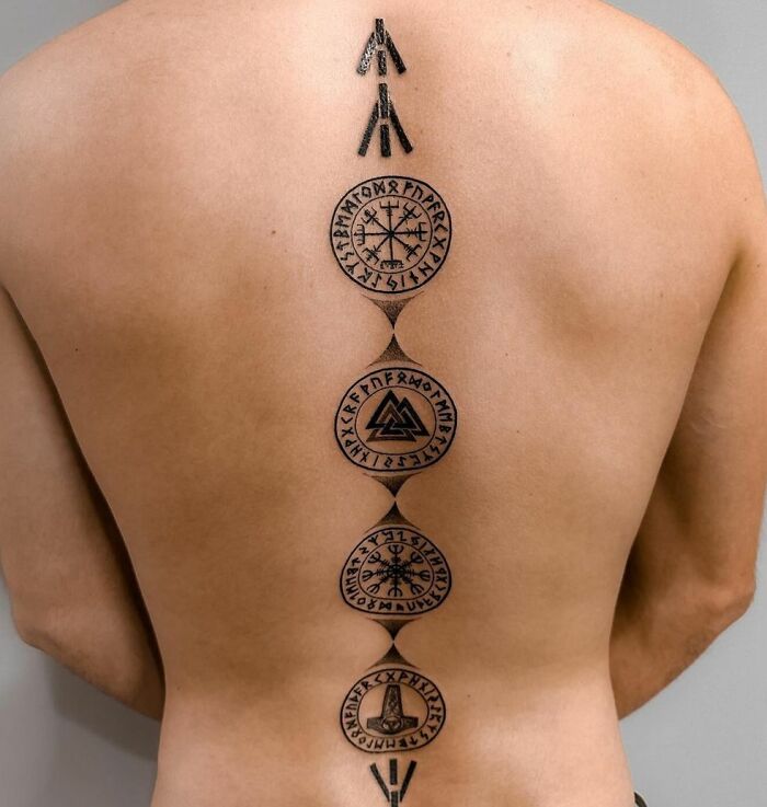 Intricate spine tattoo with Nordic symbols, showcasing beautiful detail and design along the back.